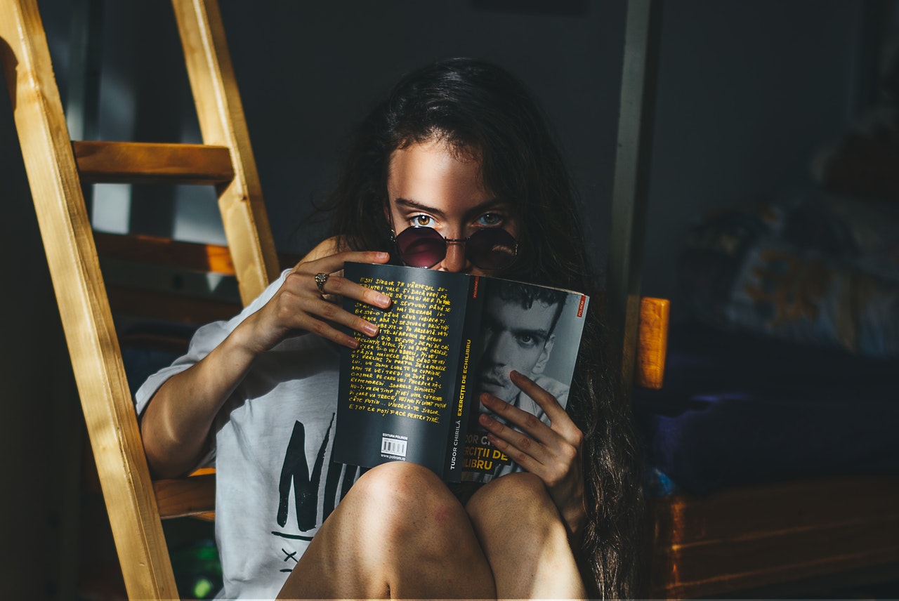 Young lady with prescription sunglasses reading a book