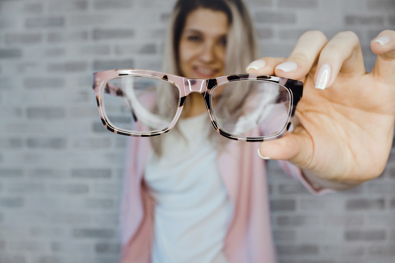 Lady holding out cool pink prescription eyeglasses